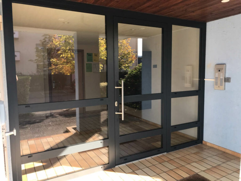 Pose d'une grande porte d'immeuble vitrée au style moderne